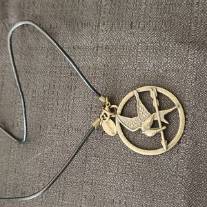 HANGER GAMES METAL ART PENDANT WITH 18IN LEATHER CORD NECKLACE.
